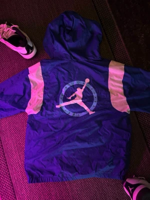 *SÄLLSYNT* Blå och vit JORDANS vindjacka - Snygg blå vindjacka från Jordan med vita detaljer på ärmarna och stor Jumpman-logga på ryggen. Jackan har huva och dragkedja framtill. Tillverkad i lätt och tåligt syntetmaterial, perfekt för en sportig och avslappnad stil.