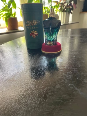 Jean Paul Gaultier Le Beau Le Parfum - Snygg parfymflaska från Jean Paul Gaultier, Le Beau Le Parfum. Flaskan har en unik design formad som en manlig torso i blått och grönt glas med gulddetaljer och röd botten. Kommer med originalförpackning i matchande färg. 75 milliliter flaska med ca 65ml kvar.