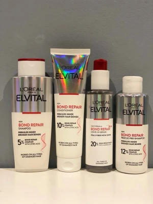 L'Oréal Elvital Bond Repair set - Säljer ett set med L'Oréal Elvital Bond Repair produkter: schampo, balsam, leave-in serum och rescue pre-schampo. Förpackningarna är i silver, vitt och rött med moderna detaljer. Produkterna är framtagna för att stärka och reparera skadat L'Oréal Elvital Bond Repair set med citronsyra.