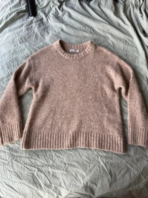 Beige stickad tröja  - Mysig beige stickad tröja med rund halsringning och ribbade muddar vid ärmslut och nederkant. Tröjan har en rak passform. Materialet är mjukt och fluffigt. 
