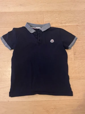 Moncler pike 14anni/164 - Säljer nu min mörkblåa moncler piké i Stl 14anni/164. Den är i superbra skick. Har ett jätte jätte litet hål som knappt syns. Mycket använd men väll omhändertagen. Hör av er vid funderingar
