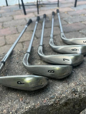 Golfklubbor vänster - Säljer ett set med fem golfklubbor, järn 5, 6, 7, 8 och P. Klubborna är i metall med silverfärgade huvuden och skaft. Det är callaway x hot golfklubbor med fattning vänster 