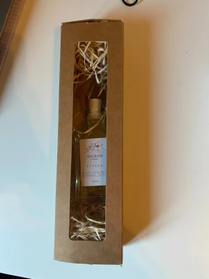 Citrus doft flaska med pinnar i presentförpackning - Fräsch citrusdoft med pinnar  i en stilren glasflaska på 50 ml, levereras i en snygg brun presentförpackning med fönster och dekorativt fyllnadsmaterial. Perfekt som gåva till någon som gillar friska och lätta dofter.