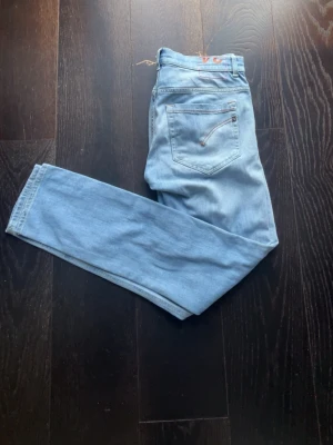 Dondup George - W32 - Ljusblå jeans i snygg skinny fit-modell. Klassisk femficksmodell med dragkedjedetalj på bakfickorna. Fint skick och en ljusblå färg som passar till det mesta. Säljer eftersom de inte kommer till användning.