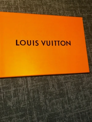 Vita Louis Vuitton sneakers - Säljer ett par vita Louis Vuitton sneakers med ikoniska monogramdetaljer i grått och präglat mönster på lädret. Skorna har chunky sula och klassisk low-top design. Kommer i original orange box. Perfekta för dig som vill sticka ut med lyxig streetstyle.