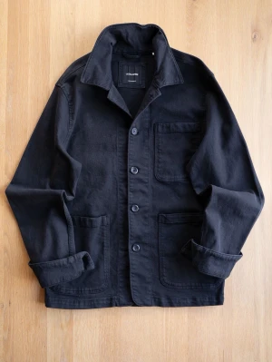 Svart overshirt från Jack & Jones - Stilren svart overshirt från Jack & Jones med tre stora utanpåfickor och knäppning framtill. Skjortkrage och raka ärmar. Tillverkad i ett kraftigare bomullstyg som ger en avslappnad men ändå snygg look.