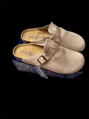 Birkenstock Boston Soft Footbed, storlek 43, helt nya - Säljer ett par Birkenstock Boston i storlek 43.  Helt nya och oanvända. Skorna är i nyskick och kommer med originalkartong och etiketter.  Modell: Birkenstock Boston Storlek: 43 Färg: Beige Fotbädd: Soft Footbed Skick: Helt nya, oanvända Originalkartong: Ja  Boston är en av Birkenstocks mest populära modeller. Enkel design som passar både hemma och till vardags.
