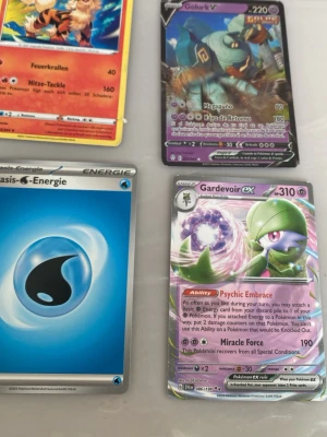 4 Pokémon kort  - Fyra Pokémonkort säljes: Gardevoir EX, Golurk V, ett vattenenergi-kort och ett eldkort. Korten har färgstarka illustrationer och är tryckta på klassiskt glansigt samlarkortmaterial. Perfekt för samlare eller Pokémonfans som vill utöka sin kortlek.