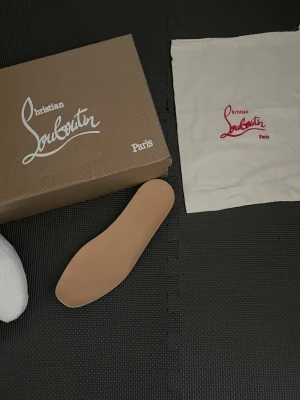  Christian Louboutin förpackning  - Beige innersula från Christian Louboutin. Tillbehör till skor, levereras med originalkartong och dustbag med logga. Passar perfekt för dig som vill fräscha upp dina Louboutin-skor eller behöver en extra innersula.