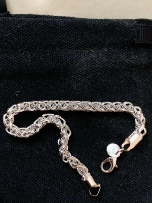 Flätat silverarmband med karbinlås - Snyggt flätat armband i silverfärg med robust karbinlås. Armbandet har en elegant och tidlös design med tätt sammanflätade länkar som ger ett exklusivt intryck. Perfekt accessoar för dig som gillar stilrena smycken i metall.