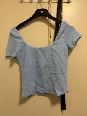 Ljusblå croppad topp med kort ärm - Snygg ljusblå croppad topp med korta ärmar och bred, djup urringning. Perfekt till jeans eller kjol för en trendig look. Tillverkad i mjukt bomullsmaterial som känns skönt mot huden.