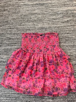 Rosa blommig volangkjol - Kort kjol i rosa med blommigt mönster och flera volanger från bikbok i strl M. Knappt använd, ordinarie pris, ca 300kr.