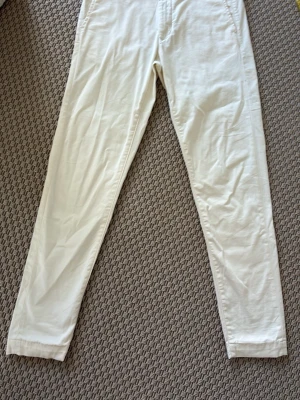 These glory days vita chinos - Säljer ett par vita chinos med rak passform och diskreta sidofickor. Byxorna har en klassisk look och är tillverkade i ett lätt material som känns svalt och skönt. Perfekta för dig som gillar en clean och enkel stil.