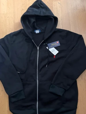 Svart polo Ralph lauren zip tröja  - Polo Ralph Lauren tröja – svart, S  Helt ny Polo Ralph Lauren tröja i svart färg, storlek S. Aldrig använd, säljes endast eftersom den är för stor för mig.  📏 Storlek: S 🎨 Färg: Svart ✨ Skick: Helt ny