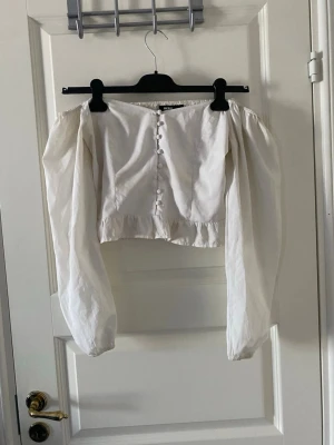 Vit topp med långa armar - En super fin vit topp med långa armar som hänger ner för axlarna. Knapparna går inte att knäppa upp.