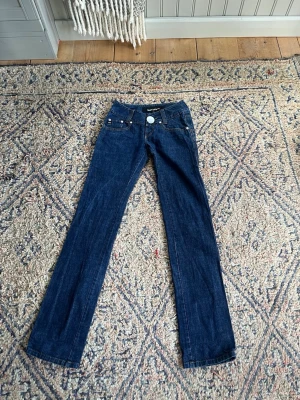 Mörkblå bootcut jeans - Snygga mörkblå bootcut jeans med klassiska fem fickor och kontrastsömmar. Jeansen har en låg midja och raka ben som går ut något nedtill. Perfekta till sneakers eller boots för en avslappnad look.