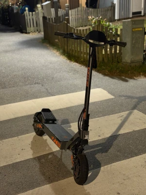 Svart och orange elscooter Kukirin G2 - Säljer en svart och orange elscooter av modellen Kukirin G2. Scootern har robust ram i metall, bred fotplatta och stora hjul för extra stabilitet. Utrustad med handtag, display och skivbromsar. Perfekt för att ta sig fram snabbt i stan.