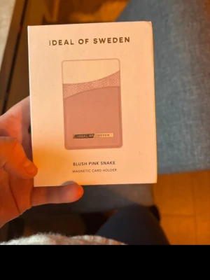 Blush Pink Snake magnetisk kortficka - Snygg magnetisk kortficka från iDeal of Sweden i färgen Blush Pink Snake. Kortfickan har ett elegant ormmönster och är designad för att fästas på mobilskal. Perfekt för att ha dina viktigaste kort nära till hands. Tillverkad i konstläder.