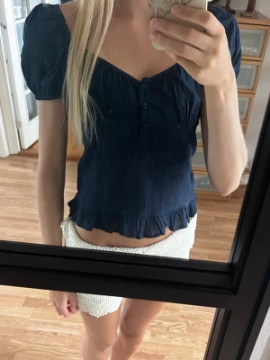 Mörkblå blus med volang och puffärm - Söt mörkblå blus med puffärmar och knappar framtill. Blusen har volangkant nedtill. Storlek 34/xs och från Nelly. Fint skick💕💕
