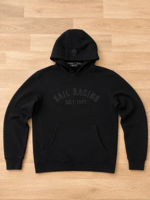 Svart Sail Racing Tröja - Säljer en svart/mörkgrå hoodie från Sail Racing med broderad text 'SAIL RACING EST. 1977' på bröstet. Hoodien har en klassisk huva och en stor magficka framtill. Perfekt för dig som gillar stilrena och sportiga plagg.