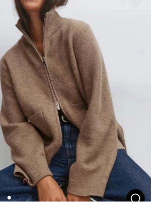 Beige ziptröja i ullmix - Mysig beige ziptröja med hög krage och två fickor framtill. Tillverkad i en mjuk ullmix med avslappnad passform och ribbade muddar. Perfekt att slänga på sig över en t-shirt eller skjorta för en chill look.