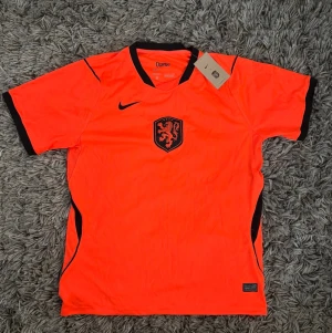 Plick:🇳🇱 Nederländerna Landslagströja - Säljer en riktigt snygg och stilren Nederländerna-landslagströja från Nike i den ikoniska orangeröda färgen med svarta/mörkblå detaljer och det klassiska KNVB-emblemet på bröstet! 💥 Perfekt till matchdagar, träning eller som en fräsch streetwear-piece. 