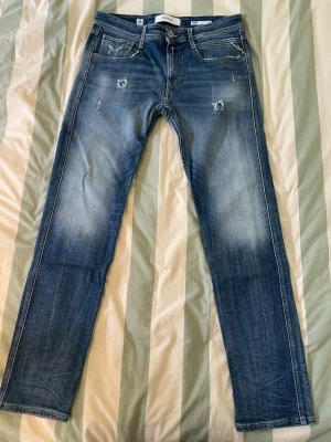Blå Replay jeans Anbass - Säljer ett par snygga Replay jeans i blå färg med en lätt tvättat look och några  estetiska slitningar. Storlek: 32/32 Modell: Anbass slimfit