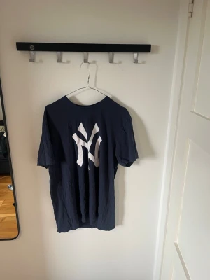 Mörkblå t-shirt Yankees - Säljer en mörkblå t-shirt med en stor vit Yankee logo. T-shirten har klassisk passform och korta ärmar. 