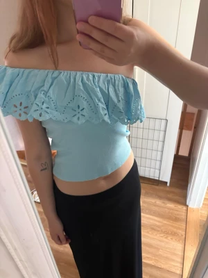 Ljusblå offshoulder topp med volang - Supersöt ljusblå offshoulder topp med bred volang och broderade detaljer. Toppen är croppad och har en figurnära passform, perfekt för sommarens alla tillfällen. Materialet känns mjukt och lätt mot huden. denna är barnstrlk men passar s-xs