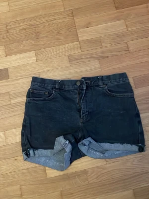 Svarta jeansshorts Ralph Laurent  - Säljer ett par svarta jeansshorts med upprullad kant och klassisk femficksdesign. Shortsen har dragkedja och knapp framtill samt bälteshällor. Perfekta för sommaren och har en avslappnad, loose passform. De är från Ralph Laurent , jag foxade kanterna på de så att de sitter bra