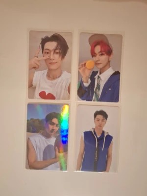 Fyra ENHYPEN photocards - Säljer ett set med fyra ENHYPEN photocards med olika medlemmar. Korten har färgstarka motiv och baksidor med text som 'ROMANCE: UNTOLD' och 'MANIFESTO'. Perfekt för samlare av K-pop merch eller fans av gruppen.