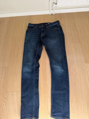 Mörkblå raka jeans - Snygga mörkblå jeans med raka ben och klassisk femficksdesign. Jeansen har subtila slitningar framtill och kontrastsömmar. Tillverkade i ett mjukt denimtyg som ger en skön passform. Perfekta till en avslappnad stil.