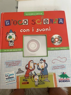 Gioco Scienza con i suoni bok - En färgglad illustrerad barnbok på italienska med titeln 'Gioco Scienza con i suoni'. Boken har hårda pärmar i rött och vitt och innehåller ett CD-fodral med ljudspår. Den är fylld med lekfulla illustrationer och experiment om ljud och djurens läten.fast vet ej hur är med cd skivan, 