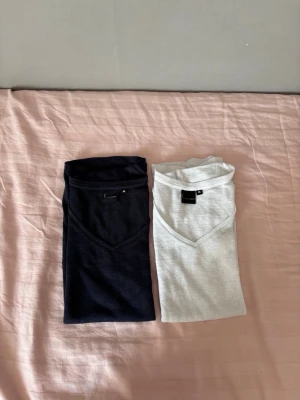 Två basic t-shirts med v-ringning - Säljer två enkla t-shirts i svart och ljusgrått med v-ringad hals. Båda är kortärmade och gjorda i mjuk bomull, perfekta till vardags. Passformen är normal och de är lätta att matcha med olika outfits.