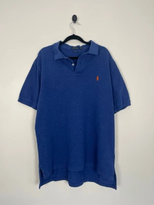Polo Ralph Lauren Pikétröja XL Blå Classic Fit Orange Pony 100% Bomull - Polo Ralph Lauren Pikétröja XL Blå Classic Fit Orange Pony 100% Bomull  • Storlek: XL • Färg: Royal Blue • Passform: Classic Fit  • Krage: Ribbad pikékrage med tvåknapps stängning • Material: 100% bomull  Skick: Plagget är i väldigt fint skick utan defekter. Eventuella anmärkningar anges alltid tydligt i beskrivningen och visas på bilderna.  Nypris: Cirka 1 500 kr.  📦 Skickas snabbt och packas omsorgsfullt. 💬 Hör gärna av dig om du har frågor eller vill se fler bilder. 🤝 Samfrakt erbjuds vid köp