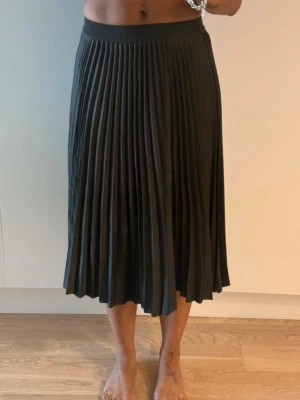 Mörkgrön plisserad kjol - Snygg mörkgrön kjol med plisserad design och bred resår i midjan. Kjolen har ett klassiskt och stilrent utseende som passar perfekt till många olika looks. 