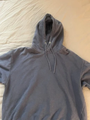 Mörkblå hoodie från 157 - Säljer en mörkgrå hoodie från 157 med klassisk huva och dragsko. Hoodien har en enkel och stilren design utan tryck eller mönster.
