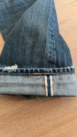 Vintage Levi’s 505 LVC Selvedge - Klassiska blå jeans från Levi's med rak passform och fem fickor. Jeansen har en snygg tvättad look med slitningar och detaljer i kopparfärgade nitar. Tillverkade i bomull med Levi's ikoniska läderpatch bak i midjan. Taggade som W32 men sitter som W30. Mått skickas gärna vid intresse.