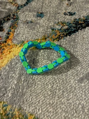 Grönt och blått Wacky Tracks - Säljer ett färgglatt Wacky Tracks i plast med länkar i grönt och blått. Wacky Tracks har en lekfull design och kan formas till nästan allt. De klickande ljudet är som ett nedsatt stress ljud.