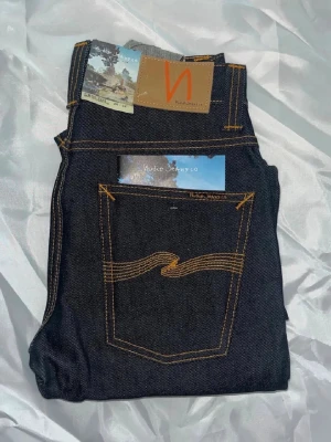 Nudie jeans Grim Tim  - Helt nya! Nudie jeans i modellen Grim Tim. Midja 33cm, längd 106cm. Tyvärr så har jag ingen bild när jag bär jeansen på.  för bättre inblick i passformen rekommenderar jag att googla på modellnamnet. För storleksguide kolla måtten noggrant då jeansen alltid kan vara uppsydda heller krympta och jag ej tar emot returer :)  Nya4