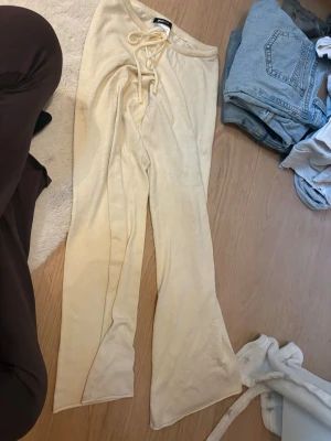 Gula mjukisbyxor med utsvängda ben - Säljer ett par ljusgula mjukisbyxor med utsvängda ben och dragsko i midjan. Byxorna har en mjuk och skön känsla, perfekta för chill dagar hemma. Materialet är mycket lent och mysigt. 