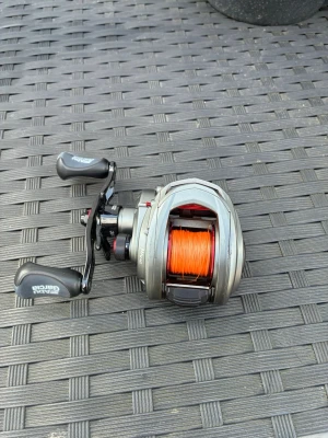 Abu Garcia multirulle med orange lina - Säljer en Abu Garcia multirulle i metall med svart handtag och detaljer i rött. Rullen har en spole med orange fiskelina och ergonomiska grepp. Perfekt för dig som gillar fiske och vill ha bra kontroll på kastet.