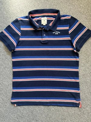 Randig pikétröja från Lee Cooper - Mörkblå pikétröja från Lee Cooper med klassisk krage och knäppning framtill. Helt ny, hör av dig vid funderingar eller behov av fler bilder!🤗