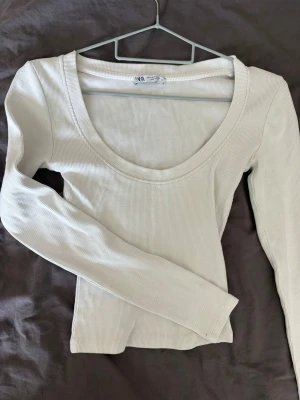 Zara ribbad topp - Säljer denna fina ribbad topp från Zara i storlek S. Vit/off-white färg med figurnära passform, rund halsringning och långa ärmar.  Toppen är använd relativt mycket men är fortfarande i väldigt fint skick. Det finns endast ett pyttelitet hål längst ut vid ena ärmen, vilket syns på första bilden. I övrigt finns inga defekter och toppen är väl omhändertagen. ✨  Storlek: S  Färg: Vit/off-white  Ribbad & figurnära  Märke: Zara  Litet hål vid ärmslutet, se bild  Pris kan diskuteras vid smidig affär!