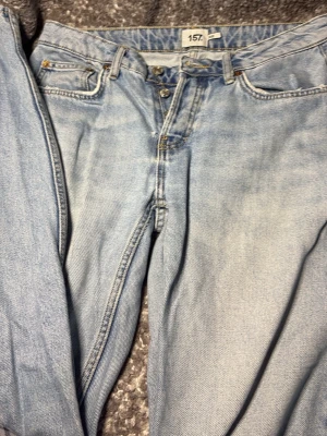 Ljusblå raka jeans med mid waist  - Säljer ett par ljusblå jeans med raka ben och mid waist lite baggy. Jeansen har en avslappnad passform och är tillverkade i denim. Perfekta för en trendig och avslappnad stil.