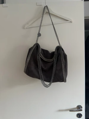 Stella martency liknande väska  - Stella martency liknande väska❤️ handväskan är  med silverfärgade kedjor som axelrem och runt kanterna. Väskan har en mjuk, slouchy form och är tillverkad i ett material som liknar mocka. Perfekt för dig som gillar en cool och trendig look.perfekt till skolan också ❤️köparen står för frakt 