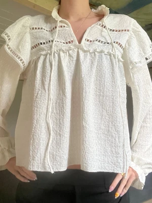 Vit blus med spets och knyt - Säljer en vit blus med långärmade puffärmar och dekorativa spetsdetaljer samt knytband vid halsen. Märket : HM, storlek M men sitter som S. Nyskick.