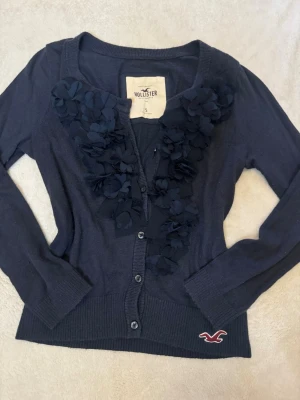 Mörkblå Hollister kofta Vintage - Säljer en skitsnygg kofta från Hollister. Koftan sitter skit snyggt på och har fina detaljer! Pris kan diskuteras och ärmarna är kortare i modellen! Mått kan skickas privat💕
