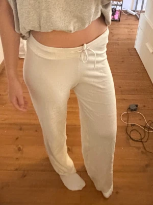 Vita mjukisbyxor - Säljer ett par vita mjukisbyxor med rak passform och dragsko i midjan. Byxorna är tillverkade i ett mjukt och bekvämt material som passar perfekt för chill dagar hemma. Enkel och stilren design utan synligt märke.
