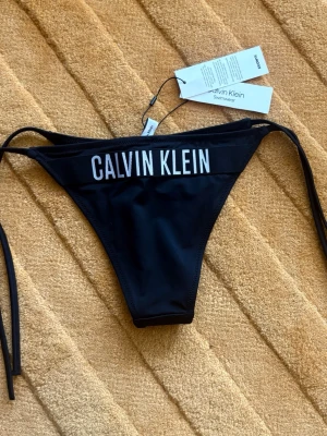 Ny Calvin Klein Svart Bikinitrosa - Strl.XS - Helt nya med lappar kvar enligt bilder.  Strl. XS (reglerbar storlek via sidobanden)  Nypris 499kr  Se gärna mina övriga annonser för bundlerabatter och samfrakt!